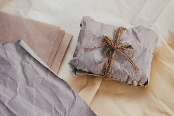 Soft parcel wrapped into old craft paper and tie. Crumpled background texture. Gift shop. Materials for transportation and shipping. - Zdjęcie, obraz