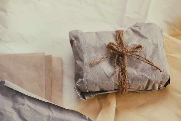 Soft parcel wrapped into old craft paper and tie. Crumpled background texture. Gift shop. Materials for transportation and shipping. - Foto, Bild