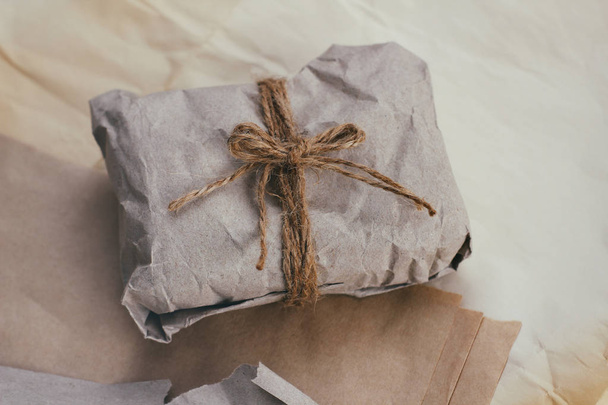 Soft parcel wrapped into old craft paper and tie. Crumpled background texture. Gift shop. Materials for transportation and shipping. - Foto, Imagem