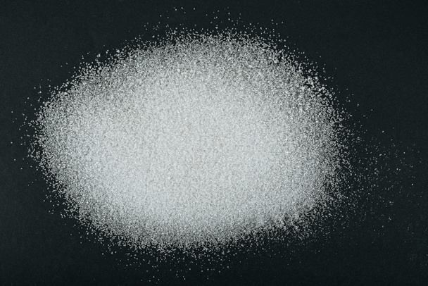 вид кристаллов белого гранулированного сахара на черном фоне
 - Фото, изображение