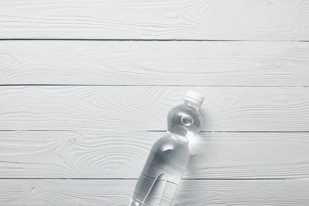 Draufsicht auf Flasche mit Wasser auf weißem Holzhintergrund mit Kopierraum - Foto, Bild