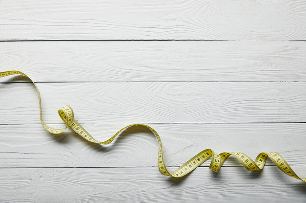 top view yellow measuring tape on wooden white background with copy space - Photo, Image