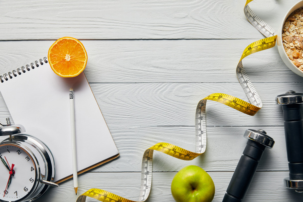 ylhäältä mittanauha, aamiaismuroja kulhoon lähellä omena, oranssi, muistikirja, käsipainot, herätyskello ja lyijykynä puinen valkoinen tausta kopiotilaa
 - Valokuva, kuva