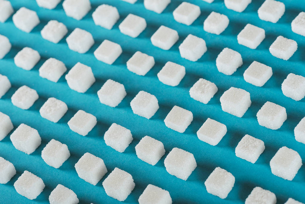 кубики белого сахара, расположенные рядами на голубой поверхности
 - Фото, изображение