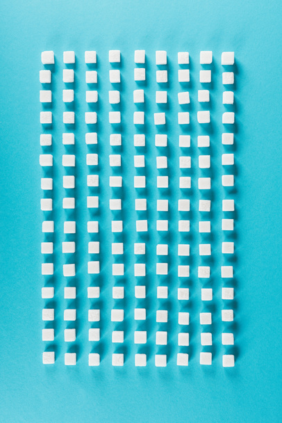top view of white sugar cubes arranged in rows on blue surface - Valokuva, kuva