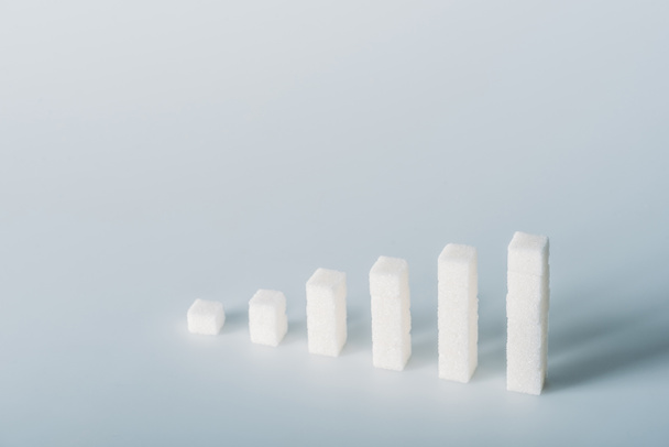 stacks of white sugar cubes on grey background with copy space - Fotó, kép