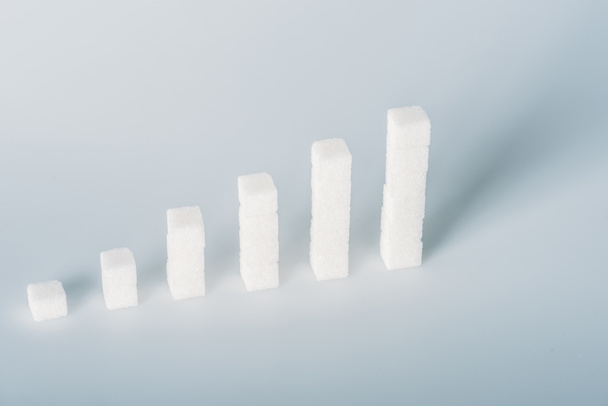 white sugar cubes arranged in stacks on grey background with copy space - Φωτογραφία, εικόνα