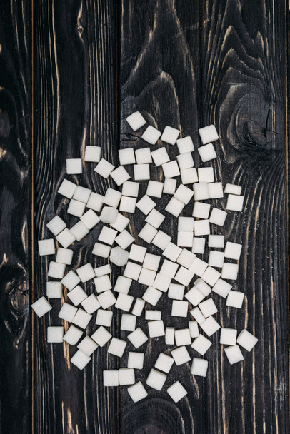 top view of white sugar cubes on black wooden background  - Photo, Image