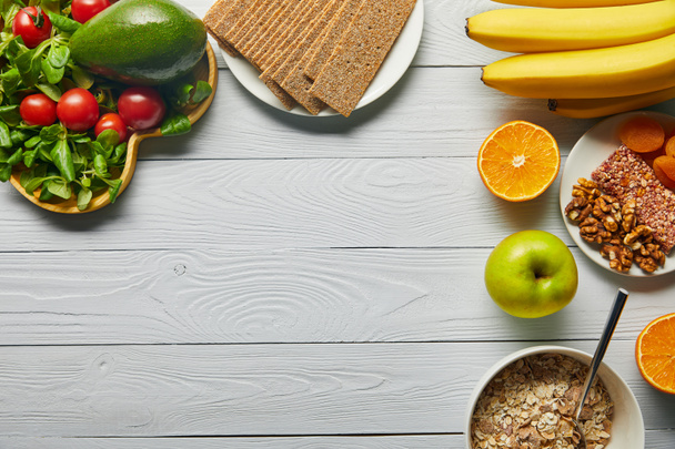 top view of fresh fruits, vegetables and cereal on wooden white background with copy space - 写真・画像