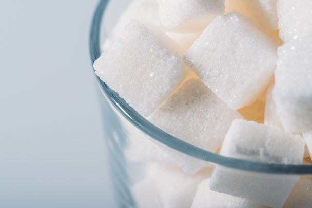 primo piano vista di cubetti di zucchero bianco in vetro su sfondo grigio
 - Foto, immagini