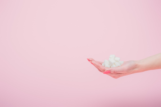 vista ritagliata donna con una manciata di cubetti di zucchero bianco su isolato su rosa
 - Foto, immagini