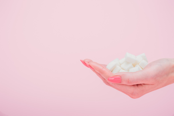 wykadrowany widok kobiety z garścią białych kostek cukru wyizolowanych na różowo - Zdjęcie, obraz