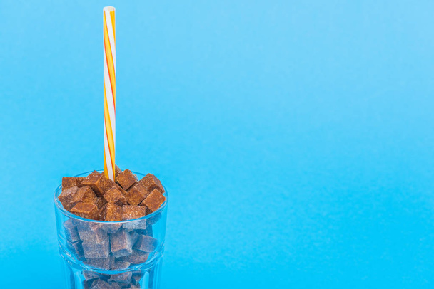 γυαλί με άχυρο και καφέ κύβους ζάχαρης που απομονώνονται στο μπλε με χώρο αντιγραφής - Φωτογραφία, εικόνα