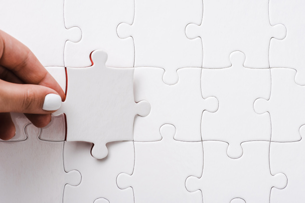 top view of woman holding white jigsaw near connected puzzle pieces - Photo, Image