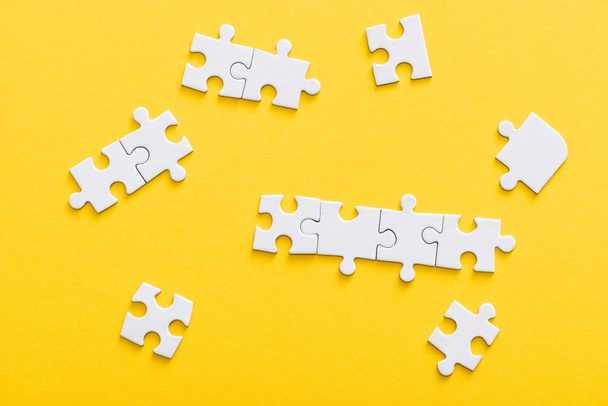 top view of connected jigsaw puzzle pieces isolated on yellow  - Foto, imagen