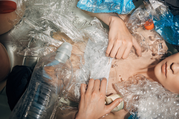 partial view of woman among plastic waste in bathtub, eco concept - Fotó, kép