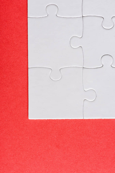 top view of white connected jigsaw puzzle pieces isolated on red  - 写真・画像