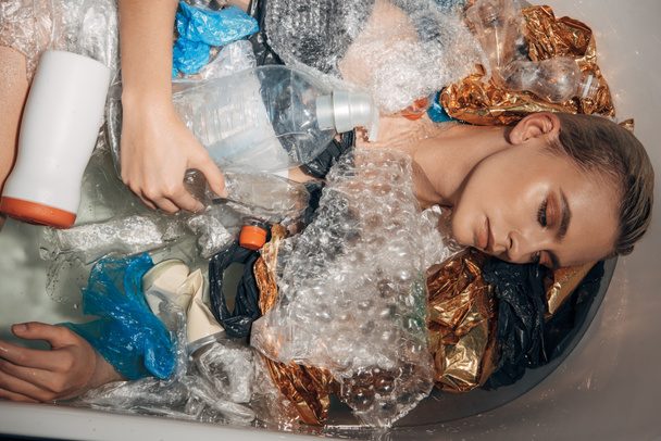 top view of young woman posing in bathtub with plastic waste, eco concept - 写真・画像