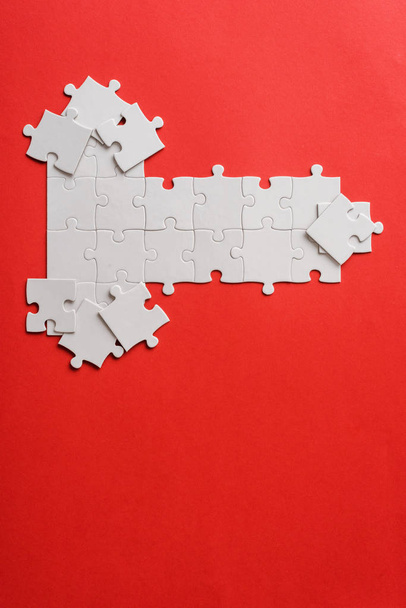 top view of white connected puzzle pieces near shapes on red  - Photo, Image
