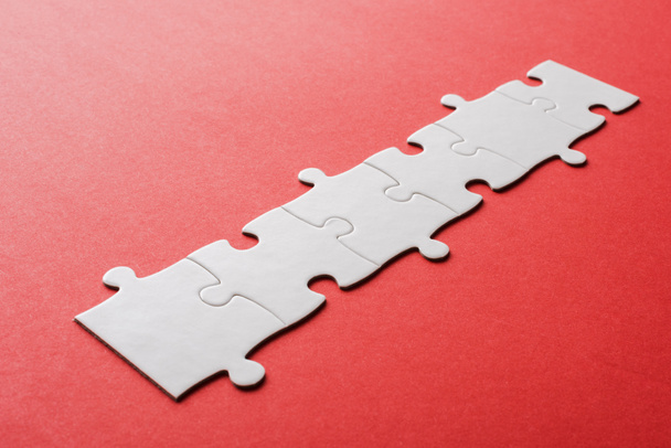 white line of connected jigsaw puzzle pieces on red  - Foto, imagen