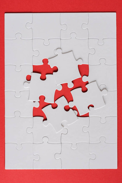 top view of white jigsaw near connected puzzle pieces on red  - Fotó, kép