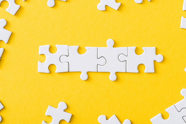 top view of connected line with white jigsaw puzzles isolated on yellow - Photo, Image