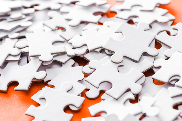 selective focus of incomplete white jigsaw puzzle pieces on orange - Фото, изображение