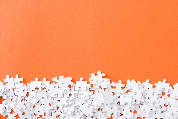 vista superior de piezas de rompecabezas blanco inacabadas aisladas en naranja con espacio de copia
 - Foto, Imagen