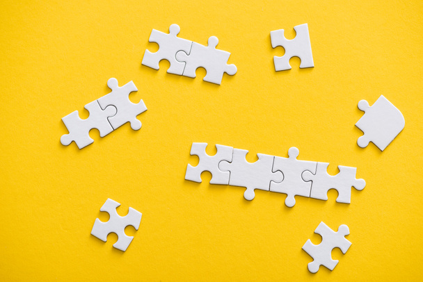 top view of connected and unfinished puzzle pieces isolated on yellow  - Photo, Image