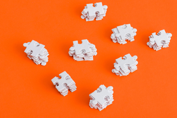 Top uitzicht van gestapelde witte puzzelstukjes op oranje - Foto, afbeelding