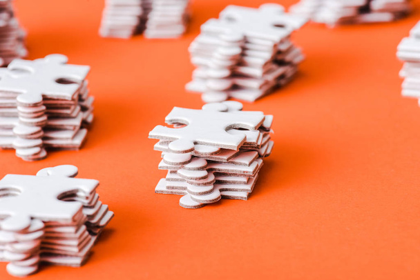 selective focus of white puzzle pieces stacks on orange - Foto, Bild