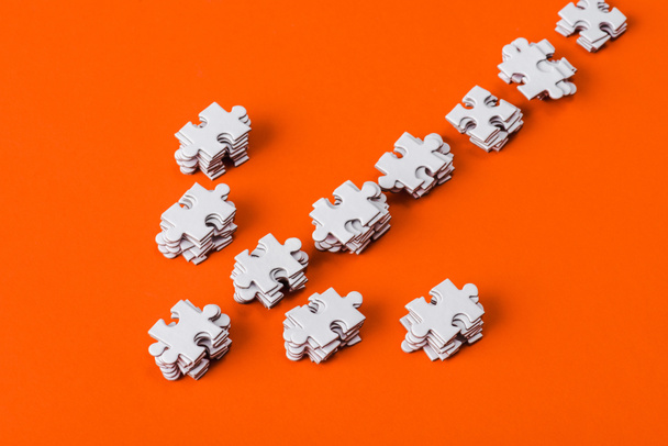 top view of direction arrow with white jigsaw puzzle pieces on orange - Photo, Image