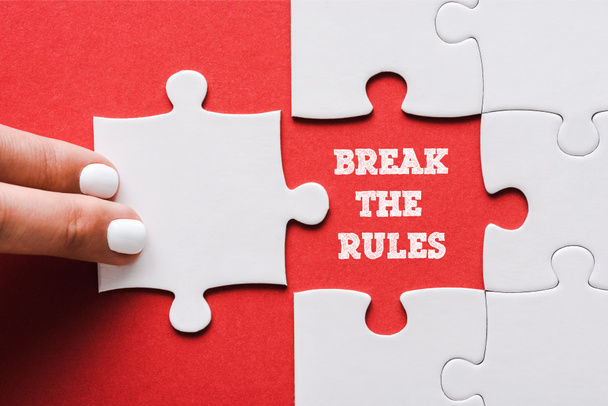 top view of woman touching jigsaw near break the rules lettering and connected white puzzle pieces and idea lettering on red - Photo, Image