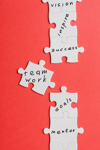 top view of white connected jigsaw near puzzle piece with words isolated on red  - Photo, Image