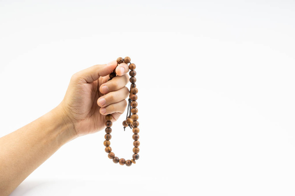 Hand holding a muslim rosary beads or Tasbih on white background. Copy space and selective focus  - Foto, Bild