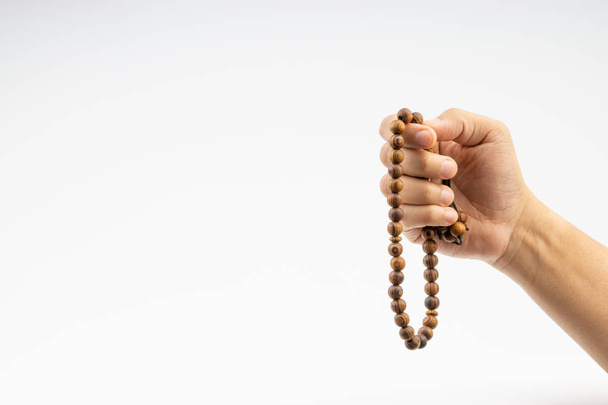 Hand holding a muslim rosary beads or Tasbih on white background. Copy space and selective focus  - Fotoğraf, Görsel