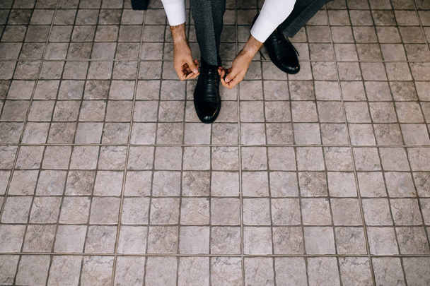 korkea kulma näkymä sulhanen musta nahka kengät sitominen kengännauhat, rajattu laukaus
 - Valokuva, kuva