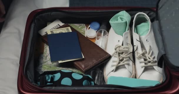Womans hands unpacking suitcase for a journey on the bed at home. Travel preparations. - Video