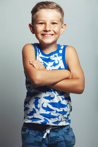 Cute little boy in white and blue sleeveless shirt posing - Foto, Imagen