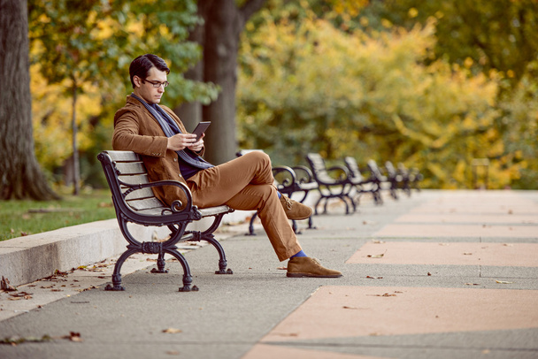 Man Relaxing In The Park Reading E-Reader - 写真・画像