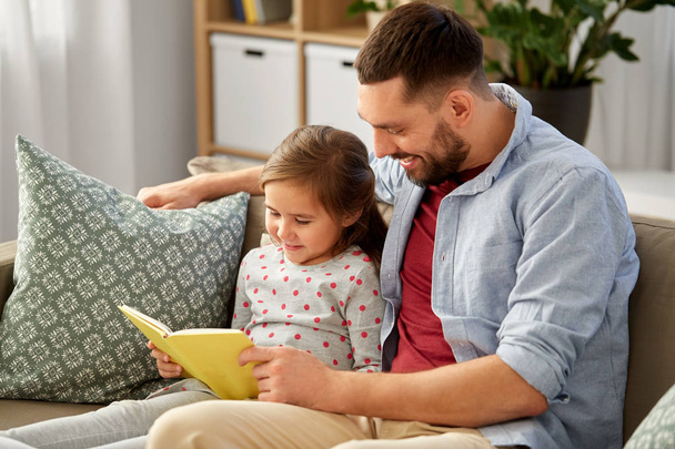 happy father and daughter reading book at home - Photo, image