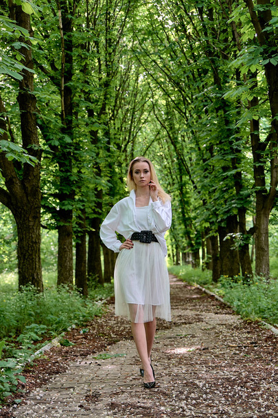 Szőke nő egyedül sétál végig a gesztenyepálya a városi parkban. Fiatal nő modern portré. - Fotó, kép
