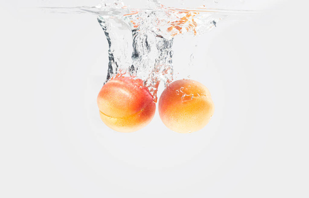Two apricots dropped water with splash - Photo, image