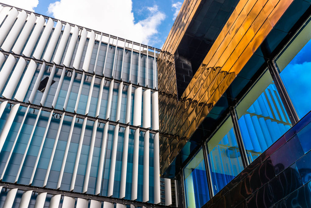 A fachada de um edifício moderno com uma fachada inovadora feita de persianas automáticas e móveis contra o fundo do céu azul com nuvens
. - Foto, Imagem