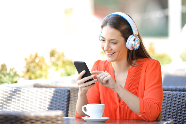 Happy woman listening to music in a coffee shop - Fotó, kép