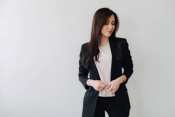 Молодая привлекательная эмоциональная девушка в деловой одежде на обычном белом фоне в офисе или аудитории
 - Фото, изображение