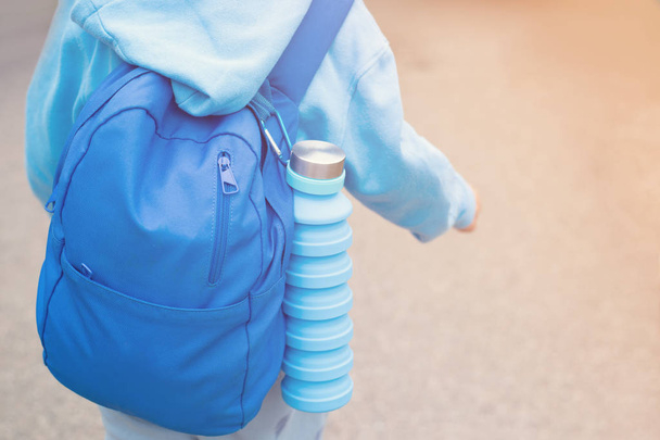 Reusable eco friendly water bottle on childs backpack - Fotoğraf, Görsel