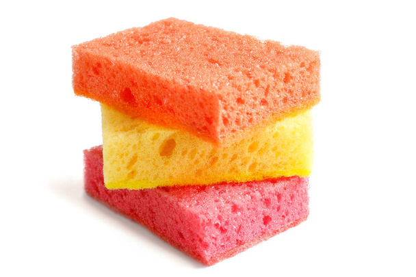 Éponges colorées pour laver la vaisselle et autres besoins domestiques. Une éponge jaune se trouve entre les lèvres orange et rouge à un léger angle. isolé
 - Photo, image