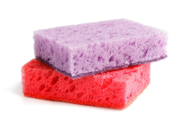 Gekleurde sponzen voor het wassen van gerechten en andere huishoudelijke behoeften. Paarse spons ligt op een rode spons in een lichte hoek. Isoleren - Foto, afbeelding