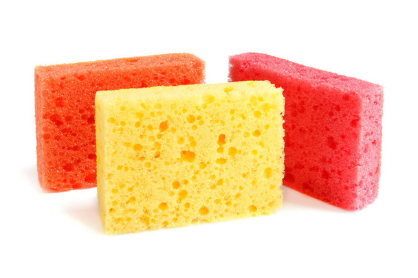 Esponjas coloridas para lavar pratos e outras necessidades domésticas. Três esponjas de cores vermelho, laranja e amarelo estão na borda. Isolar
 - Foto, Imagem